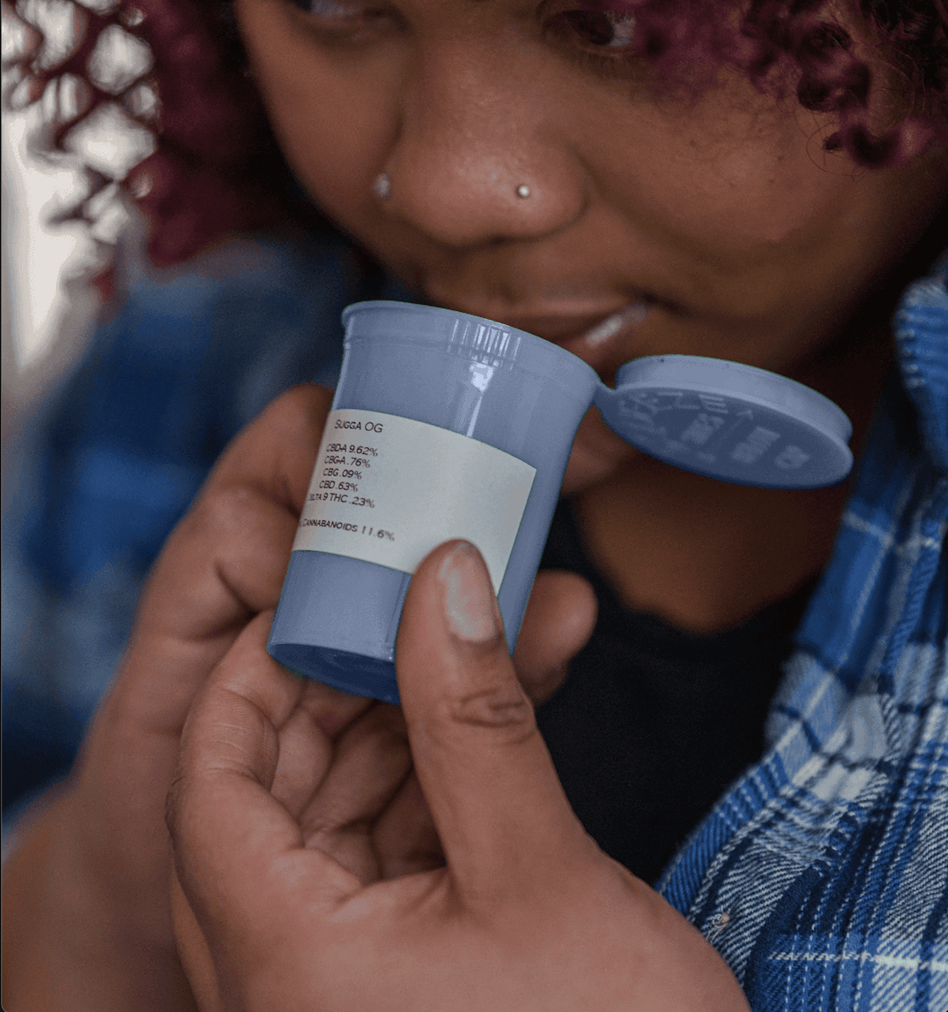 A woman smelling the inside of a blue container of cannabis to identify the terpenes.